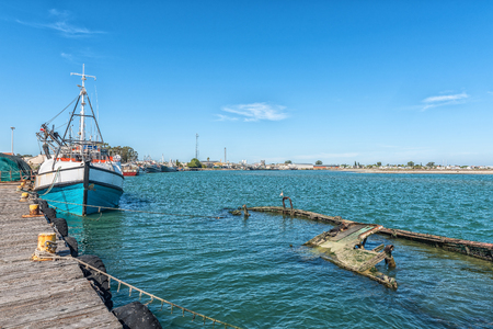 LAAIPLEK, SOUTH AFRICA - APRIL 1, 2017: Fishing ships and a sunken boat in the harbor at the mouth of the Berg River at Laaiplek on the Atlantic coast of South Africaのeditorial素材