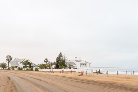 HENTIES BAY, NAMIBIA - JUNE 29, 2017: A street scene with houses on a dune and a salt road in Henties Bay, a holiday town on the Skeleton Coast of Namibiaのeditorial素材