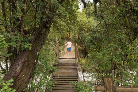 ROYAL NATAL NATIONAL PARK, SOUTH AFRICA - MARCH 17, 2018: An unidentified tourist on a pedestrian bridge over the Mahai River at the Mahai Camp Siteのeditorial素材