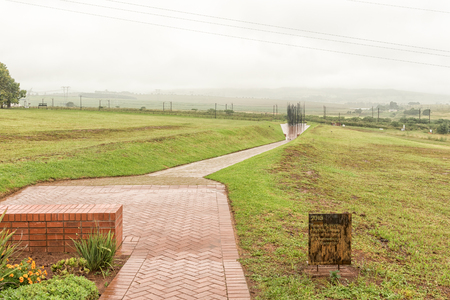 HOWICK, SOUTH AFRICA - MARCH 23, 2018: The final information plaque along the path with the statue of Nelson Mandela at his capture site in the back. At a specific viewpoint, the colums combine to form his faceのeditorial素材