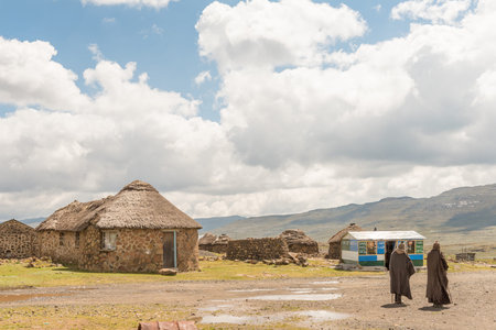 SANI TOP, LESOTHO - MARCH 24, 2018: Two Basotho men in front of a craft shop and stone huts at the...
