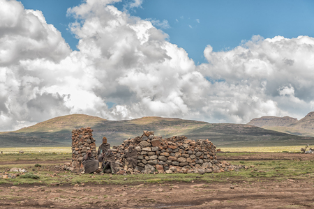 BLACK MOUNTAIN PASS, LESOTHO - MARCH 24, 2018: Unidentified Basotho people in front of a ruin in the Mamokae village at the foot of the Black Mountain Passのeditorial素材