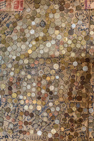 SANI TOP, LESOTHO - MARCH 24, 2018: Coins from all over the world in the pub at Sani Mountain Lodge at the top of the Sani Pass. The lodge claims the title of highest pub in Africaのeditorial素材