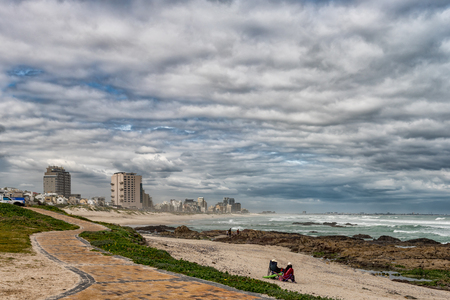 CAPE TOWN, SOUTH AFRICA, AUGUST 14, 2018: A beach scene, with apartment buildings and people, in Bloubergstrandのeditorial素材