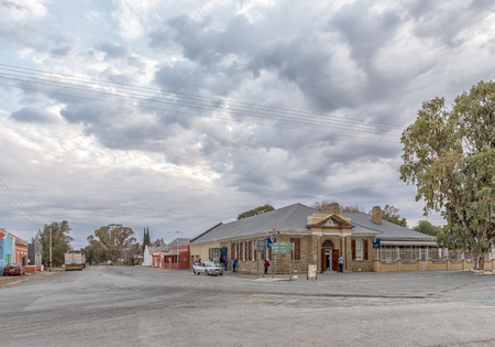 CARNAVON, SOUTH AFRICA, SEPTEMBER 1, 2018: An early morning street scene, with a bank building and houses, in Carnavon in the Northern Cape Province. Vehicles and people are visibleのeditorial素材