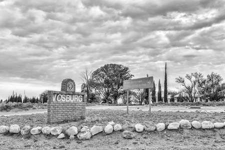 VOSBURG, SOUTH AFRICA, SEPTEMBER 1, 2018: A name board and directional sign at the entrance to Vosburg in the Northern Cape Province. Monochromeのeditorial素材