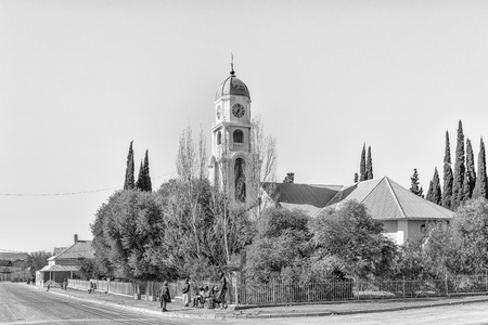 PETRUSVILLE, SOUTH AFRICA, AUGUST 6, 2018: A street scene, with the Dutch Reformed Church, in Petrusville in the Northern Cape Province. People are visible. Monochromeのeditorial素材