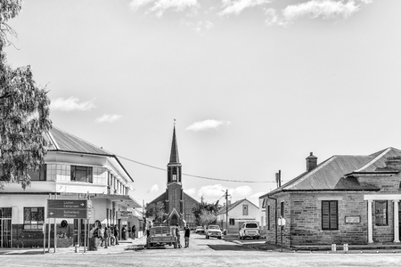 FRASERBURG, SOUTH AFRICA, AUGUST 7, 2018: A street scene, with the Dutch Reformed Church, businesses, vehicles and people, in Fraserburg in the Northern Cape. Monochromeのeditorial素材