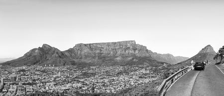 CAPE TOWN, SOUTH AFRICA, AUGUST 9, 2018: A panorama of Cape Town as seen from Signal Hill. Devils Peak, Table Mountain, Lions Head, people and vehicles are visible. Monochromeのeditorial素材