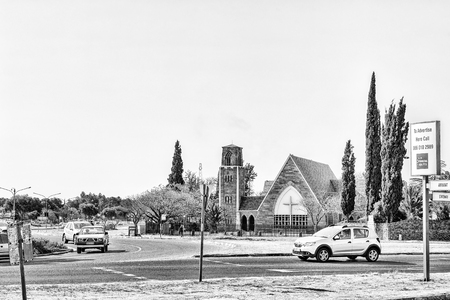 WELKOM, SOUTH AFRICA, AUGUST 2, 2018: A street scene, with the St Matthias Anglian Church, in Welkom in the Free State Province Province. Vehicles are visible. Monochromeのeditorial素材