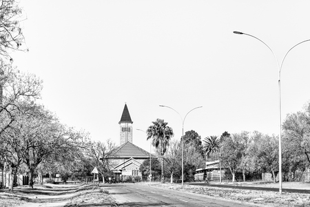VIRGINIA, SOUTH AFRICA, AUGUST 2, 2018: The Dutch Reformed Church in Virginia in the Free State Province Province. Trees and lamp posts are visible. Monochromeのeditorial素材