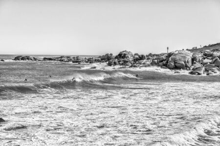 CAPE TOWN, SOUTH AFRICA, AUGUST 9, 2018: Surfers at a beach in Camps Bay in Cape Town in the Western Cape Province. Monochromeのeditorial素材