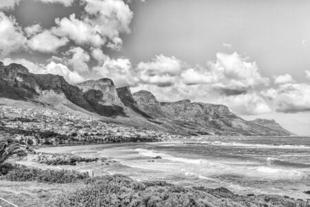 CAPE TOWN, SOUTH AFRICA, AUGUST 17, 2018: A view of the coastline in Camps Bay in Cape Town in the Western Cape Province. The 12 Apostles and buildings are visible. Monochromeのeditorial素材
