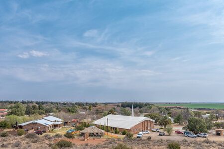 ORANIA, SOUTH AFRICA, SEPTEMBER 1, 2018:  View of Orania as seen from Monument Hill. A fete is in progress at the Afrikaans Protestant Church. Vehicles and people are visibleのeditorial素材