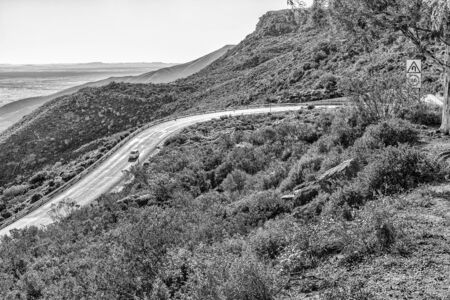 NIEUWOUDTSVILLE, SOUTH AFRICA, AUGUST 29, 2018: Vehicles are visible on the historic Van Rhyns Pass near Nieuwoudtville in the Northern Cape Province. Monochromeのeditorial素材
