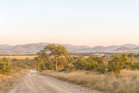 KRUGER NATIONAL PARK, SOUTH AFRICA - MAY 3, 2019: The road to the Malelane Bush Camp in the Kruger National Park. A vehicle and Malelane town are visibleのeditorial素材