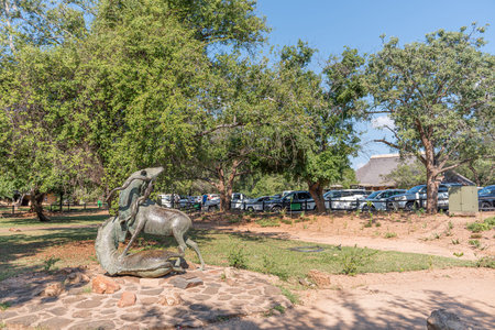 KRUGER NATIONAL PARK, SOUTH AFRICA - MAY 5, 2019: A scene in the Skukuza Restcamp. People, vehicles and a statue of two kudu bulls fighting are visibleのeditorial素材