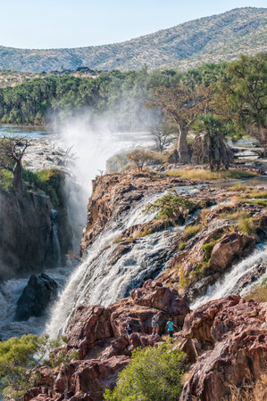 EPUPA, NAMIBIA - MAY 24, 2011: Part of the Epupa waterfalls in the Kunene River. People, baobab and...