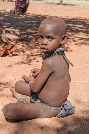 EPUPA, NAMIBIA - MAY 27, 2011: An young Himba boy posing for photographers at a Himba village near...