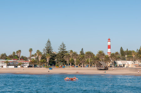 SWAKOPMUND, NAMIBIA - JUNE 18, 2012: A beach scene at the waterfront in Swakopmund. Palm trees and the historic lighthouse are visibleのeditorial素材