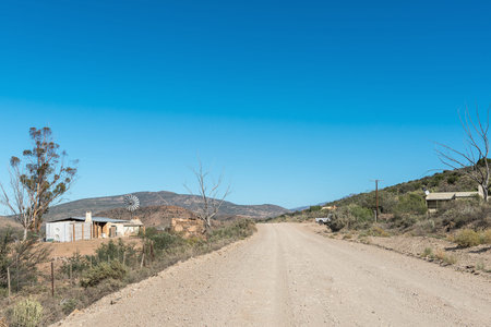 MIEREFONTEIN, SOUTH AFRICA - APRIL 7, 2021: Farms buildings, a windmill and a vehicle next to road P294のeditorial素材