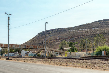TOUWS RIVER, SOUTH AFRICA - APRIL 20, 2021: Rusted pedestrian bridge at the railway station in Touws River. The name of the town is visible on the Draaiberg Mountain in the backのeditorial素材