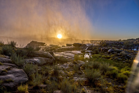 Sunrise through the spray of a flooded Augrabies Falls. Boardwalks are visibleの写真素材