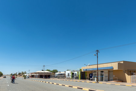 Kenhardt, South Africa - Feb 28 2023: A street scene, with a bank building and businesses, in Kenhardt in the Northern Cape Province. A power transmission route and people are visibleのeditorial素材