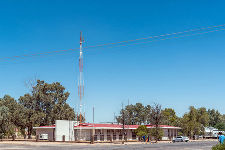 Kenhardt, South Africa - Feb 28 2023: A street scene, with the building of the Kai Garib Municipality, in Kenhardt in the Northern Cape Province. People, a vehicle and telecommunications tower are visibleのeditorial素材