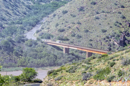 A vehicle is visible on the single lane bridge through the spray of falling water of the Gariep Damの写真素材