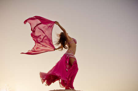 Pretty girl holding pink cloth in wind with sky backgroundの写真素材