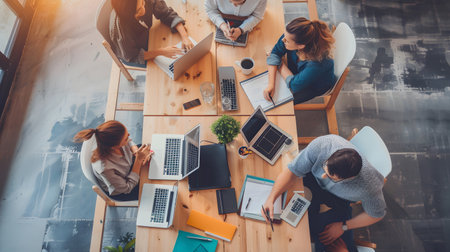 Group of professionals working together in an office top view, collaborating around a laptop during a team meeting. Great for teamwork, startup, and corporate use.の写真素材