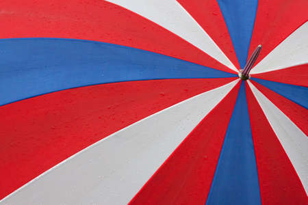 Red white and blue umbrella with rain dropsの写真素材