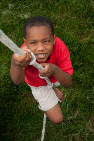 An african-american boy climbing up a rope の写真素材