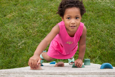 An African-American toddler climbing a play wall の写真素材