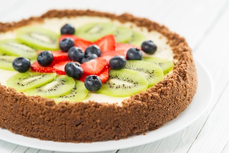 Cheesecake with kiwi, blueberry and strawberry on a plateの写真素材