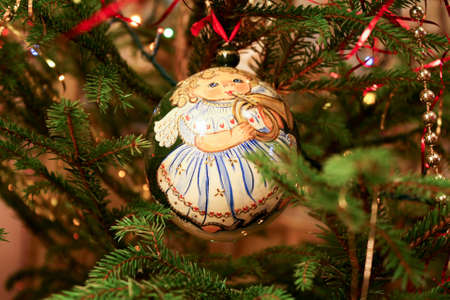 Christmas ball with the image of the girl-angel on the Christmas tree among the garlands and streamersの写真素材