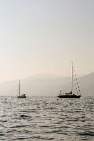 Two sailing boat on the waves of color steel and misty mountains in the distanceの写真素材