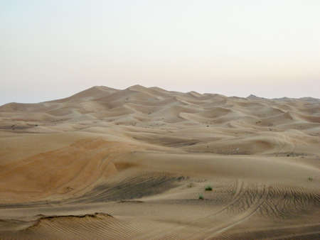 Large yellow desert sand dunes to the wheel tracks in the last rays of the sun.の写真素材