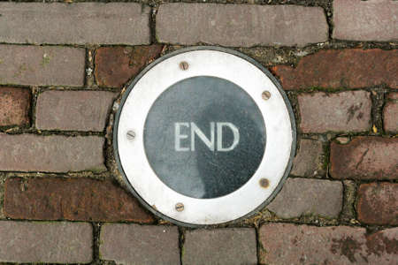 Scratched round lights with the words "End", mounted in the cobbled pavement.の写真素材