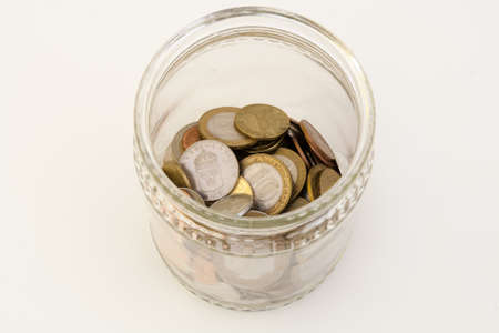 Transparent bank with coins of different metals of different denominations from different countriesの写真素材
