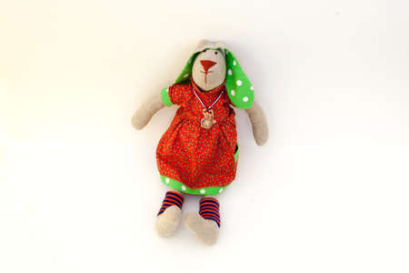 Toy bunny in red dress and socks sits. The ears are green with white polka dotsの写真素材