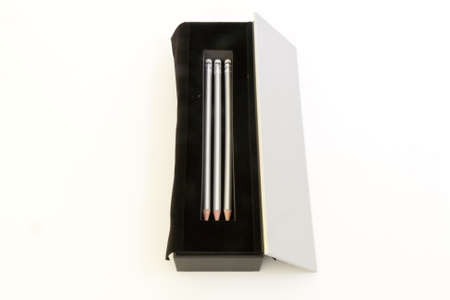 Silver pencils in a black velvet box on white background.の写真素材