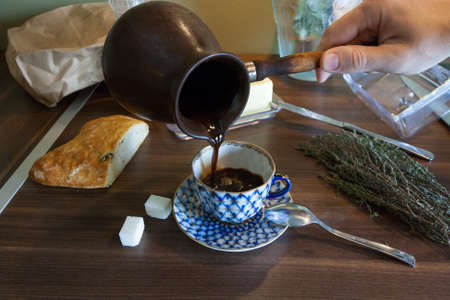 Man's hand pours coffee pots into a cupの写真素材