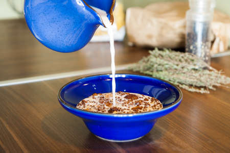 Muesli in a bowl pour the milk from milk jug.の写真素材