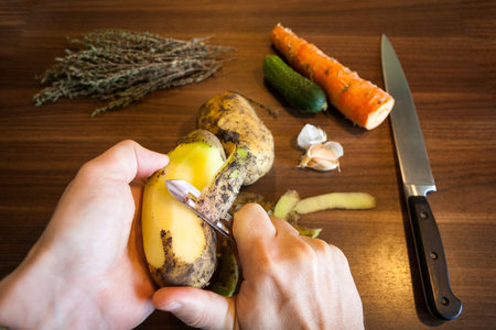 Male hands peeling potatoes peeler.の写真素材