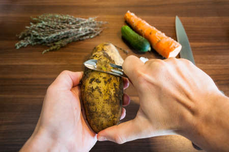 Male hands peeling potatoes peeler.の写真素材