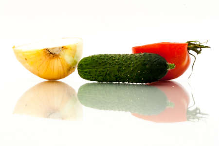 Half red tomato, half onion and green cucumber with reflections on a white backgroundの写真素材