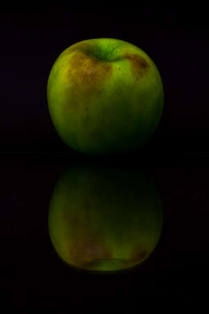 Green apple with reflection on black background.の写真素材