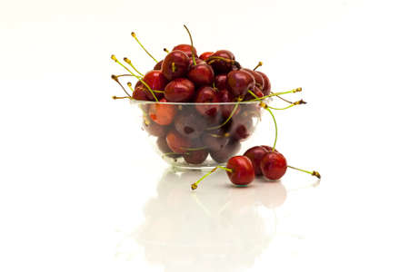 Transparent cup with red ripe cherries with reflection on white background.の写真素材